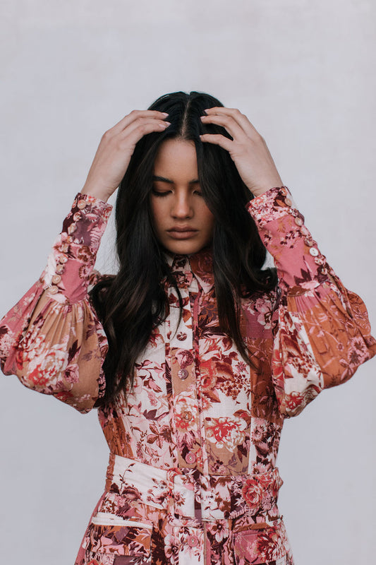 Woman wearing a floral patterned outfit against a plain background