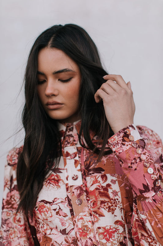 Woman wearing a floral blouse against a plain background