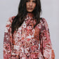 Woman wearing a floral patterned outfit against a plain background