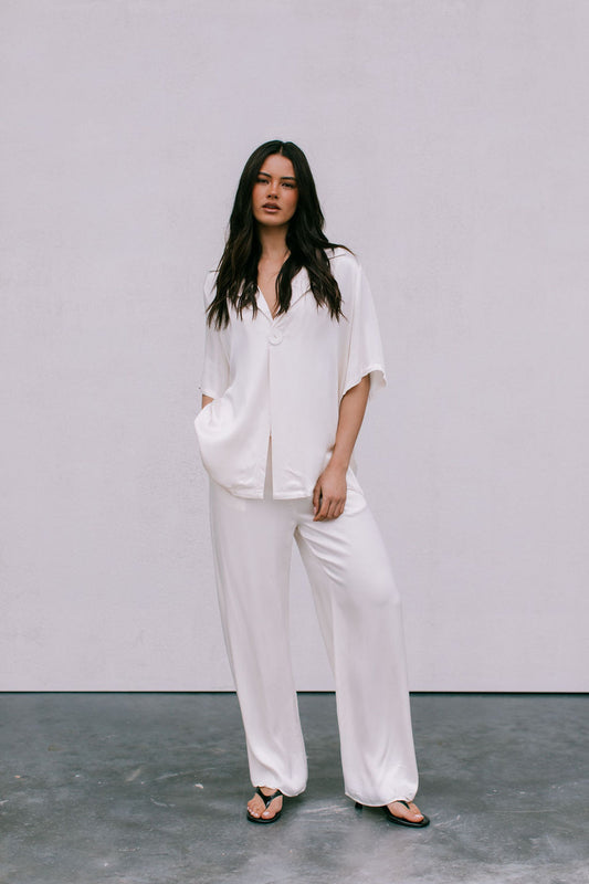 Woman wearing a white outfit standing against a plain background