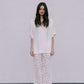 Woman wearing a white blouse and floral pants against a plain background