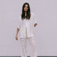 Woman wearing a white outfit with lace pants against a plain background