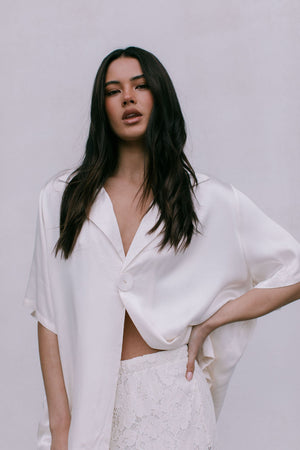 Woman wearing a white outfit against a plain background