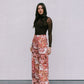 Woman wearing a brown top and floral skirt against a plain background