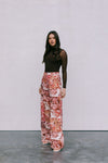 Woman wearing a brown top and floral skirt against a plain background