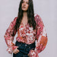 Woman wearing a floral blouse with long sleeves against a plain background