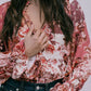 Person wearing a floral blouse with long sleeves and dark jeans on a plain background