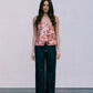 Woman wearing a floral top and dark jeans against a plain background