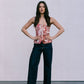 Woman wearing a floral top and dark jeans against a plain background