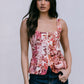 Woman wearing a floral sleeveless top against a plain background