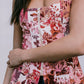 Woman wearing a floral sleeveless top with a zipper detail against a neutral background