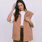 Woman wearing a tan vest over a white shirt and brown skirt on a white background