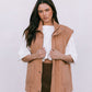 Woman wearing a brown vest over a white shirt and brown skirt on a white background