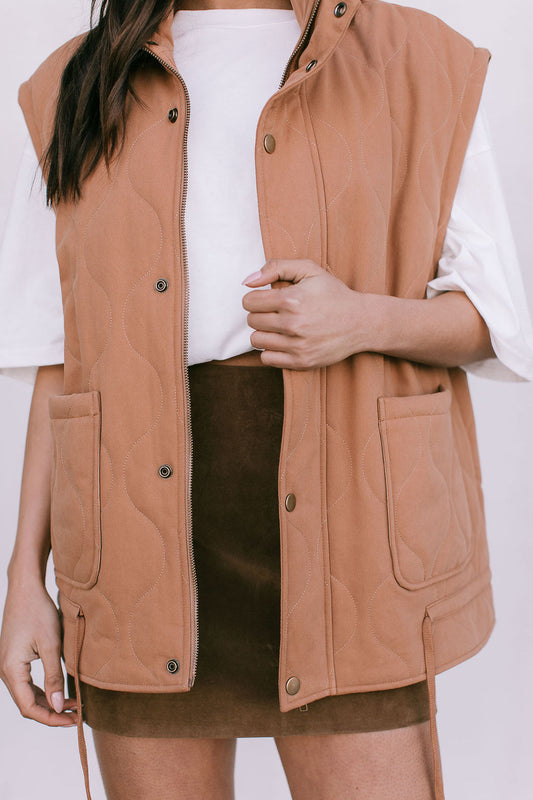 Person wearing a tan vest over a white shirt and brown skirt on a white background