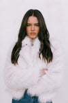 Woman wearing a white fluffy coat against a light background