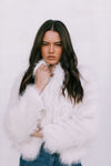 Woman wearing a white fluffy coat against a light background