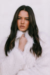 Woman wearing a white fur coat against a light background