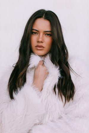 Woman wearing a white fur coat against a light background