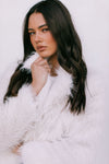 Woman wearing a white fur coat against a white background