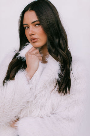 Woman wearing a white fur coat against a white background